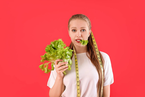 Junge Frau mit Kopfsalat und Maßband auf farbigem Hintergrund. Ernährungskonzept - Foto, Bild