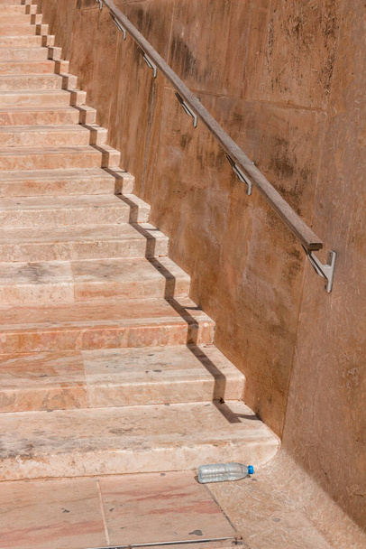 Waterbottle and shadow forming a distorted line on stairs in Malta - Photo, Image