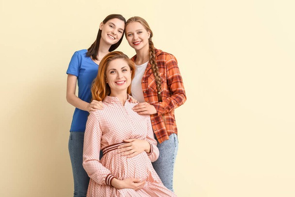 Pareja lesbiana y mujer embarazada sobre fondo de color. Concepto de maternidad subrogada
 - Foto, Imagen