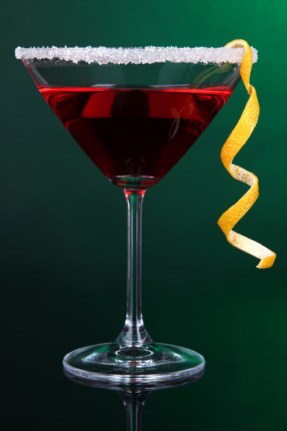 Red cocktail in martini glass on dark green background - Foto, afbeelding
