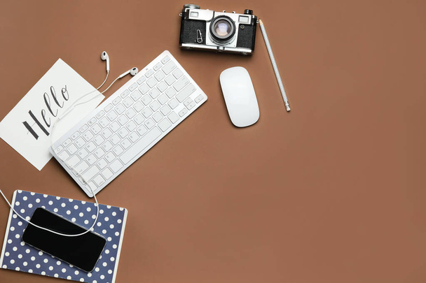 Клавиатура с ноутбуком, фотокамерой и мобильным телефоном на цветном фоне - Фото, изображение