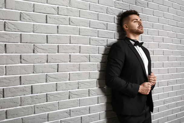 Hezký mladý muž v elegantním obleku v blízkosti cihlové zdi - Fotografie, Obrázek