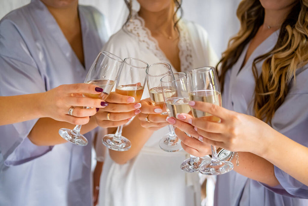 Girls in dressing gowns hold glasses of champagne at a bachelorette party at the hotel. - Photo, Image