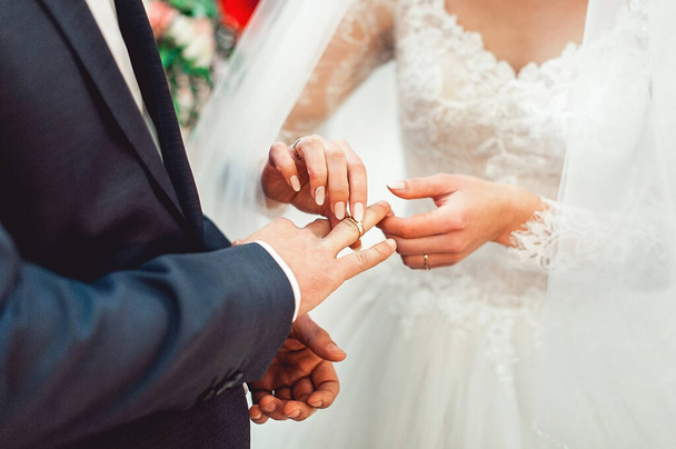 Eheringe tauschen. Braut legt einen Ring an den Finger des Bräutigams. Bräutigam im blauen Anzug. Der Brautstrauß - Foto, Bild