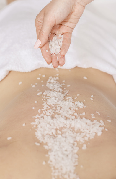 Spa scrub massage. Hands sprinkle salt on back of girl - 写真・画像