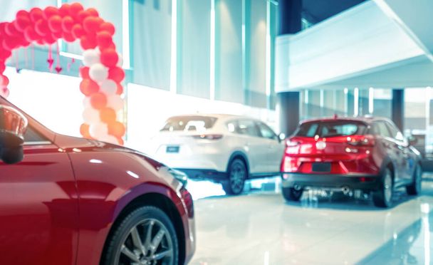 Unscharfe Rückansicht eines rot-weißen Luxus-SUV, der in einem modernen Showroom zum Verkauf steht. SUV-Auto mit Sportdesign im Showroom. Autohaus. Auswirkungen des Coronavirus auf das Konzept der Automobilindustrie.  - Foto, Bild