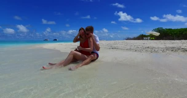 счастливая романтическая пара влюбленных, сидящая на пляже - Кадры, видео