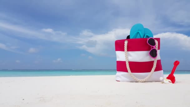 Csíkos táska papucsban és napszemüvegben a parton. Trópusi jelenet Balin, Indonéziában.    - Felvétel, videó