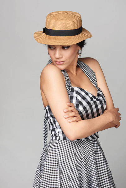 Woman in chequered summer dress and canotier straw hat looking back over shoulder - Foto, imagen