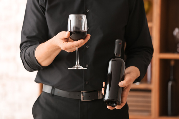 Άνθρωπος με μπουκάλι και ποτήρι νόστιμο κρασί στο κελάρι - Φωτογραφία, εικόνα