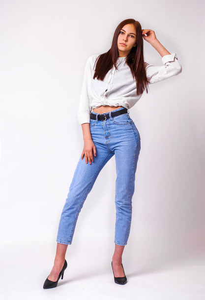 Beautiful sexy brunette woman in blue jeans. Fashion model in jeans clothing. Isolated on gray studio background - Foto, Imagem