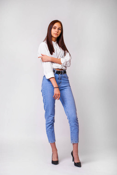 Beautiful sexy brunette woman in blue jeans. Fashion model in jeans clothing. Isolated on gray studio background - Foto, Imagen