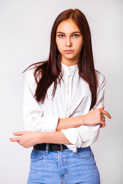 Nahaufnahme Porträt eines jungen schönen Mädchens in blauen Jeans - isoliert auf grauem Hintergrund - Foto, Bild