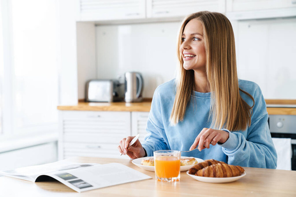 Image of cheerful young woman smiling while having breakfast - Fotoğraf, Görsel