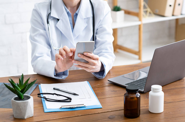 Consultazione remota dei pazienti online. Medico donna digitando sul telefono, sul tavolo
 - Foto, immagini