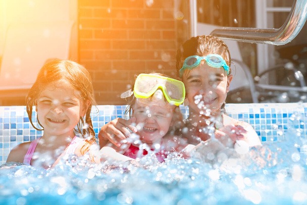 Τρία χαριτωμένα κορίτσια παίζουν στην πισίνα. Καλοκαιρινές διακοπές και ταξίδια έννοια - Φωτογραφία, εικόνα