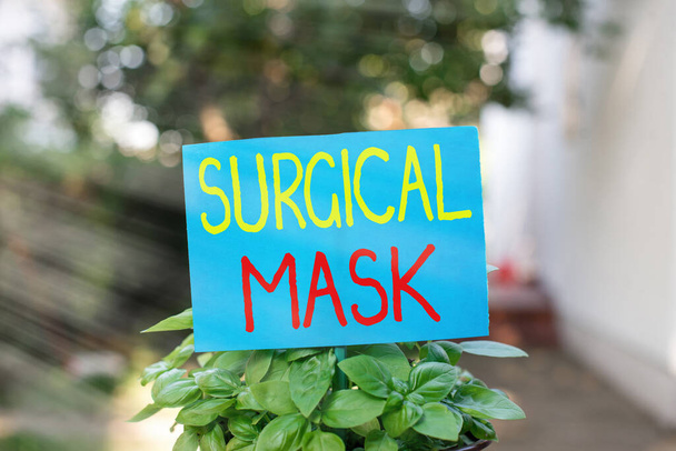 Writing note showing Surgical Mask. Business photo showcasing worn by health professionals during surgery and during nursing Plain paper attached to stick and placed in the grassy land. - Photo, Image