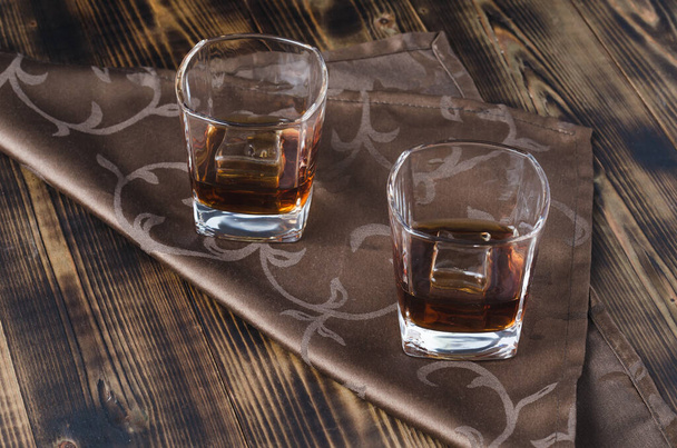 Two glasses of whiskey and ice cubes/Two glasses of whiskey and ice cubes on a napkin. - 写真・画像