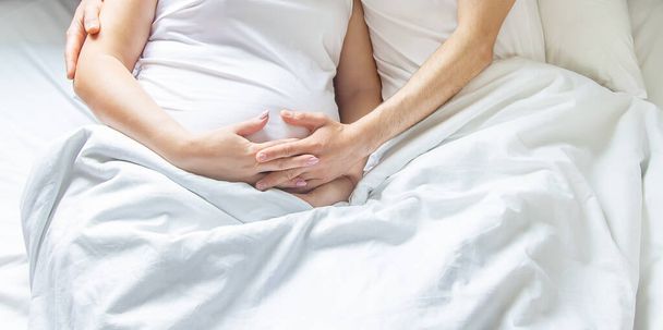 Schwangere Frau mit Mann umarmen Bauch im Bett. Selektiver Fokus. Menschen. - Foto, Bild