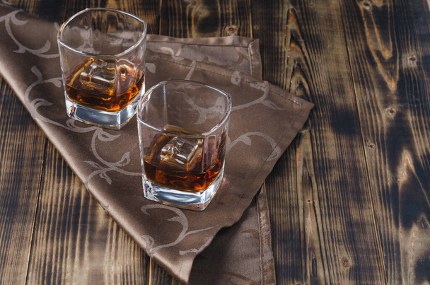Two glasses of whiskey and ice cubes/Two glasses of whiskey and ice cubes on a napkin. - Foto, Imagem