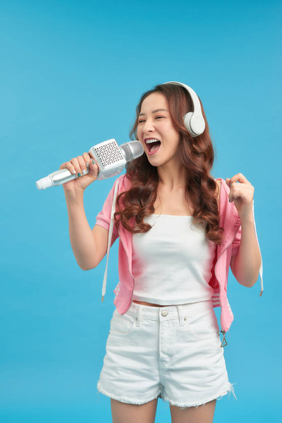 Lifestyle portrait of young cute and happy Asian student girl singing online karaoke song with microphone - Photo, Image
