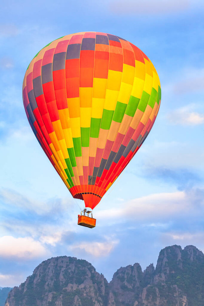 Színes hőlégballon repül át a hegyen és a dzsungelen napkeltekor. - Fotó, kép