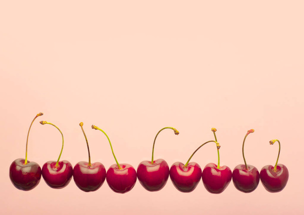 Cherry minimal background. Red summer cherry berries on a pink empty blue background. Summer fruits and food concept. - Фото, зображення