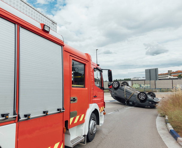 Camion-incendie rouge dans un accident de la route. Voiture renversée sur une voie publique - Photo, image