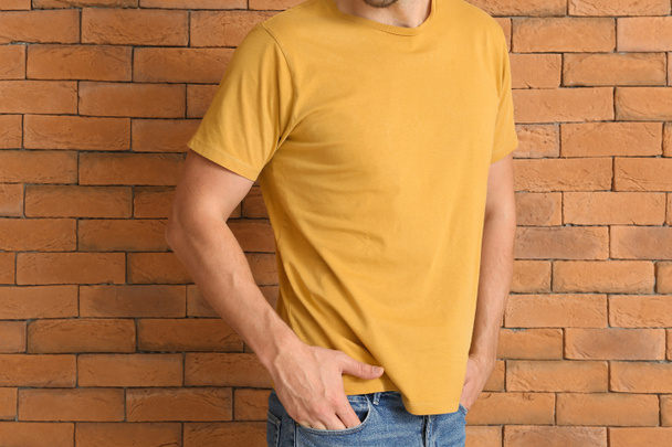 Homem em elegante t-shirt perto da parede de tijolo
 - Foto, Imagem