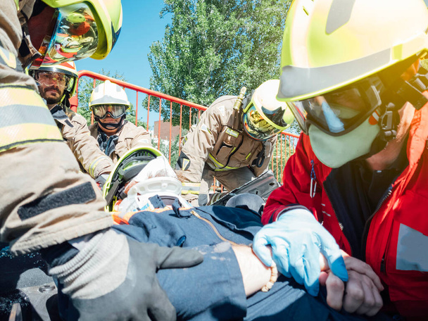 マスクの医者と4人の消防士が負傷車両の中から負傷車両を抽出します。covid 19による保護。救助と救助の概念. - 写真・画像