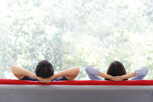 Vista traseira do encantador casal sentado e sentindo relaxar no sofá vermelho com vista para o parque ao ar livre verde. Férias. ESPAÇO COPY
. - Foto, Imagem