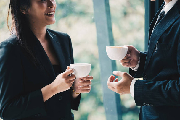 Coffee break. Group business people, standing in modern office, holding a cups, smiling standing at the window - Foto, Imagen