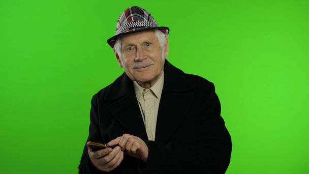 高齢者スタイリッシュな白人祖父男オンラインショッピングのためのスマートフォンを使用して - 写真・画像