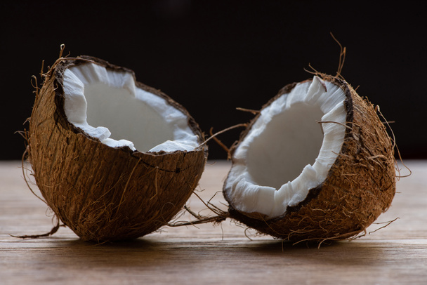 fresh tasty coconut halves on wooden table isolated on black - 写真・画像