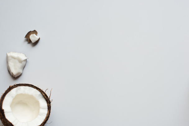 vrchní pohled na popraskané chutné kokosové půlky a kousky na bílém pozadí - Fotografie, Obrázek