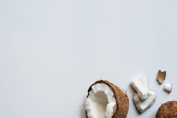 top view of fresh tasty coconut half and cracked pieces on white background - Fotografie, Obrázek