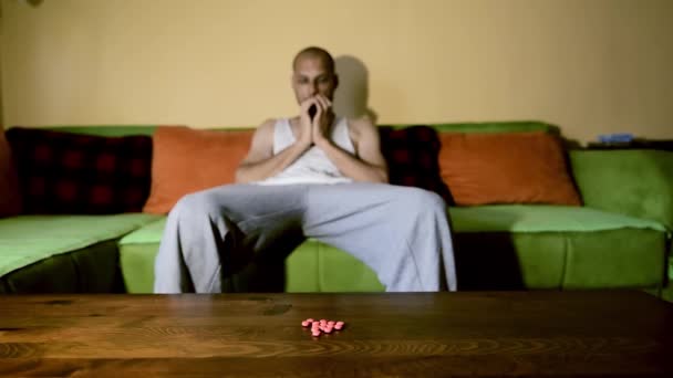 Depressed man suffering from suicidal depression want to commit suicide by overdose taking strong medicament drugs and pills pain killers sitting in his dark room selective focus moody dramatic look - Filmmaterial, Video