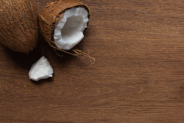 top view of fresh tasty cracked and whole coconuts on wooden table - Foto, imagen