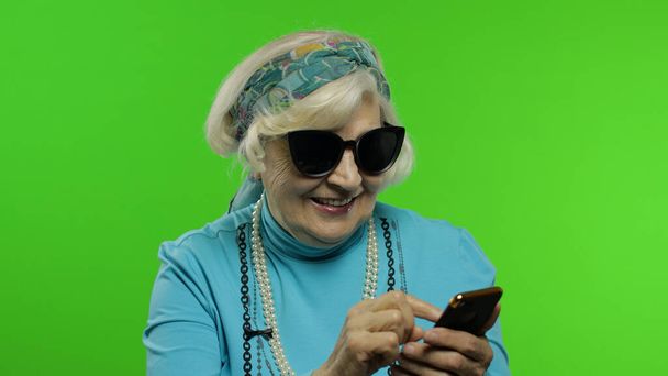 Ouderen stijlvolle Kaukasische oma vrouw met behulp van social media app op smartphone - Foto, afbeelding