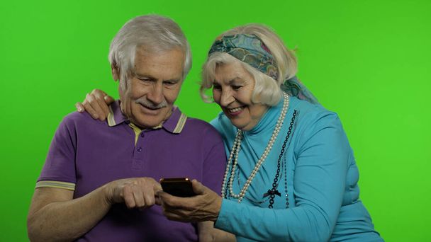 お年寄りのご高齢のご夫婦は、携帯電話でオンラインショッピングを楽しむ - 写真・画像