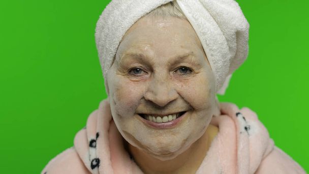 Avó idosa após o banho. Mulher velha aplicando máscara facial bolha cosmética
 - Foto, Imagem
