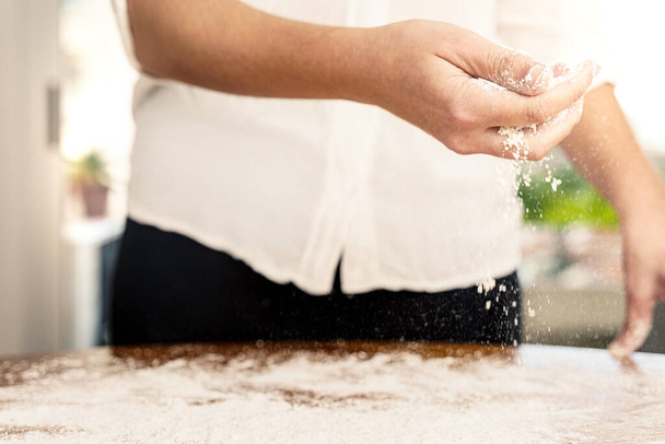 Hands of a woman sprinkling flour on the table - Photo, Image