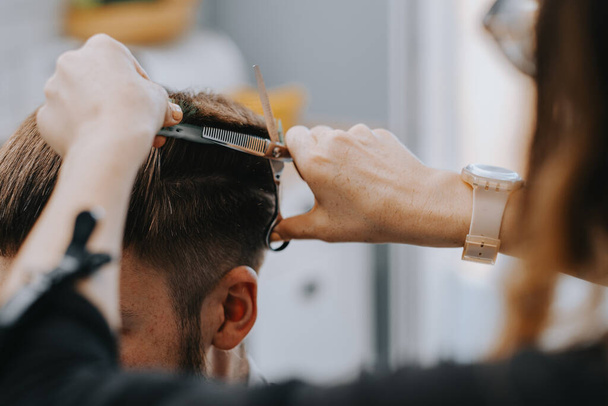 Mens haircut at home. The hairdresser cuts the hair of a man - Фото, зображення
