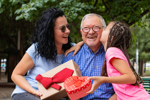 Granddaughter and her mother giving present ( surprise ) to her father ( Happy fathers day ) - Φωτογραφία, εικόνα