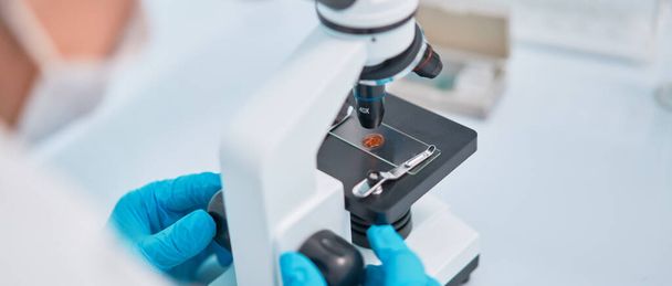 Human lab assistant in blue rubber gloves looking through microscope. - Φωτογραφία, εικόνα