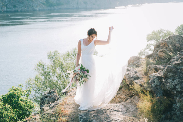 日没時に自然の中で豪華な白いウェディングドレスで花嫁 - 写真・画像