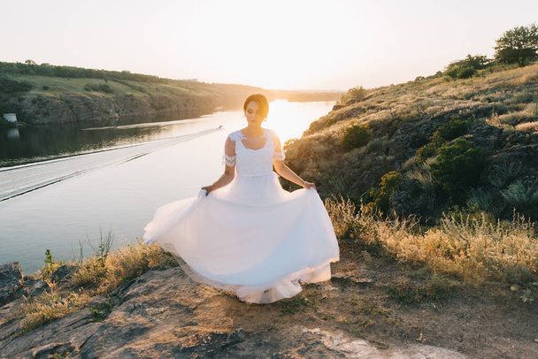 Bride in a luxurious white wedding dress in nature at sunset - Fotó, kép