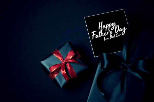 Happy Father 's Day concepto de fondo con vista superior de caja de regalo negro con cintas aisladas en el fondo tema oscuro
. - Foto, Imagen