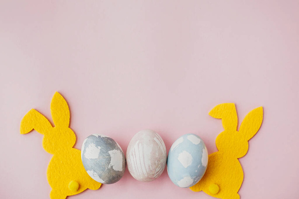Stylové velikonoční vajíčka, žlutý zajíček na růžovém papírovém stole plochý, prostor pro text. Přírodní obarvená velikonoční vajíčka a králičí dekorace. Karta maketa. Veselé Velikonoce. - Fotografie, Obrázek