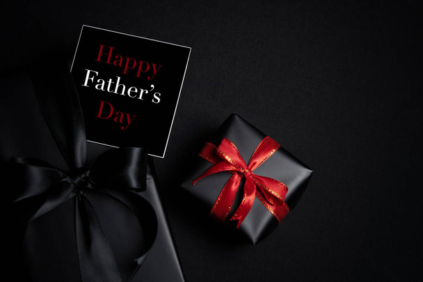 Happy Father's Day background concept with top view of black gift box with ribbons isolated on dark theme background. - Photo, Image